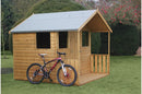 A wooden summerhouse with a single door and a small roof overhang, situated on a grassy area, with a bicycle parked in front of it.
