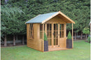 A brown wooden summerhouse with a green roof, featuring double doors and windows on the side with a green landscape in the background.