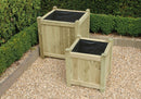 Two square wooden planters in a garden setting, one larger and one smaller, both with black planting fabric inside.