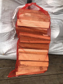 A small net of kindling wood tied with a red tie, placed on a white surface.